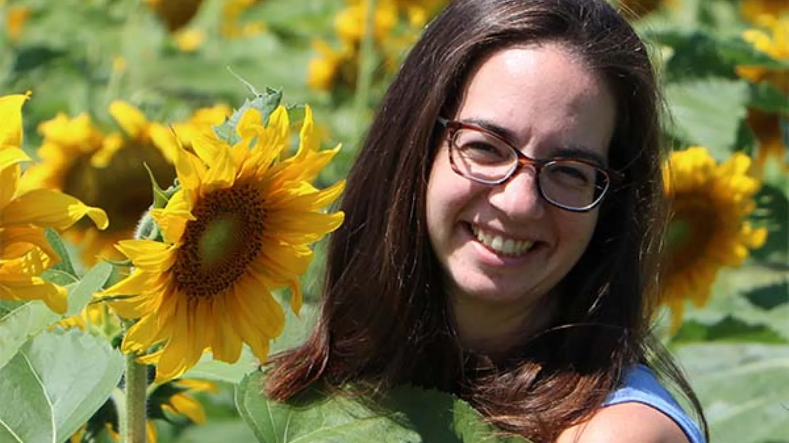 Ruth Smith in a field of sunflowers as she smiles at the camera