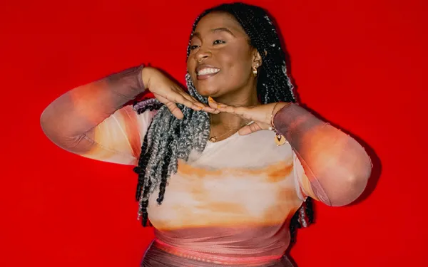 A woman smiles in front of a bright red background
