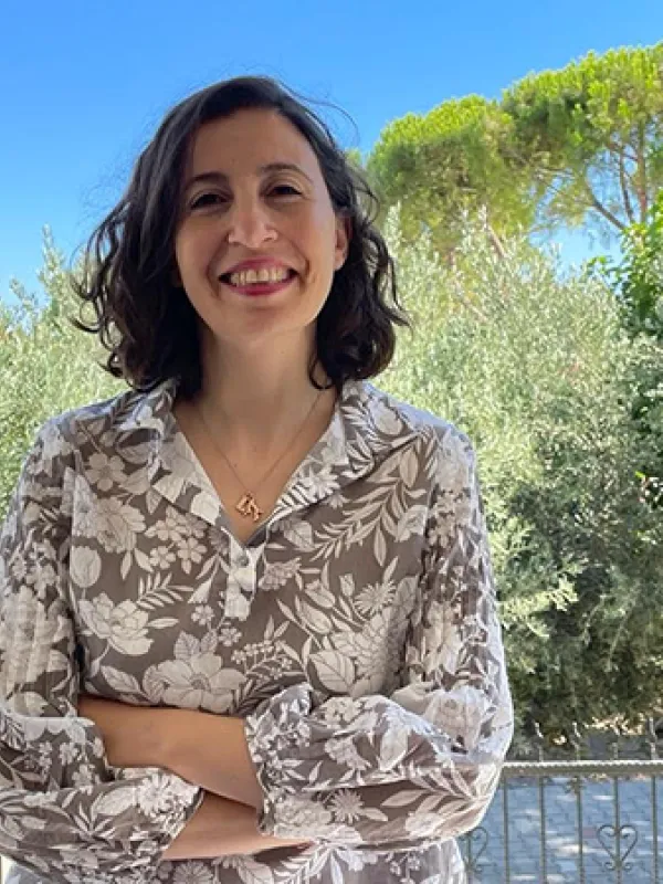 Woman with brown hair wearing flower print shirt, smiling at camera